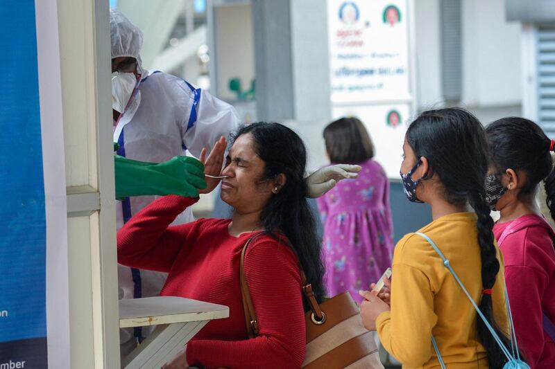 A health worker takes a swab sample for the Covid-19 coronavirus test from a passenger arriving from the United Kingdom at Anna International Airport in Chennai on December 22, 2020. (Photo by Arun SANKAR / AFP)