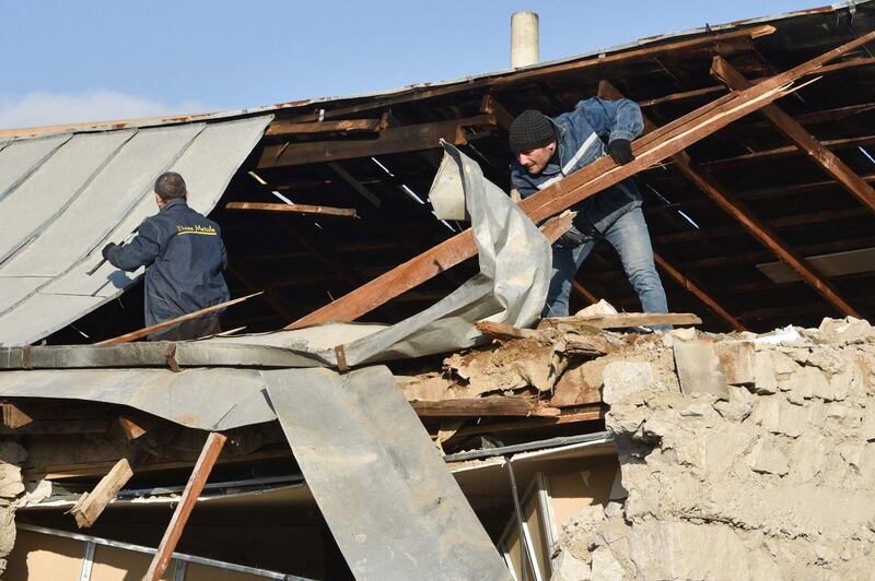 Two men repair the roof of a house destroyed by fighting in Stepanakert. AFP