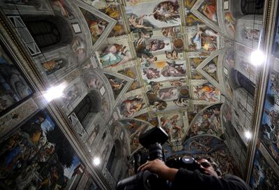 A journalist pictures the Sisitne Chapel with its new lighting during a press visit at the Vatican on October 29, 2014. The Vatican presented the LED lighting in the Sistine Chapel to illuminate the ceiling frescos. It also enstalled a new air-conditioning system and it's planning to put a limit on the number of visitors allowed in. This room where popes have been elected since the mid-15th century is visited by 6 million tourists a year to marvel at Michelangelo’s ceiling and his depiction of the Last Judgment on the altar wall.    AFP PHOTO / Filippo MONTEFORTE / MUSEI VATICANI
RESTRICTED TO EDITORIAL USE - MANDATORY CREDIT "AFP PHOTO / FILIPPO MONTEFORTE  © MUSEI VATICANI" - NO MARKETING NO ADVERTISING CAMPAIGNS - DISTRIBUTED AS A SERVICE TO CLIENTS (Photo by FILIPPO MONTEFORTE / AFP)