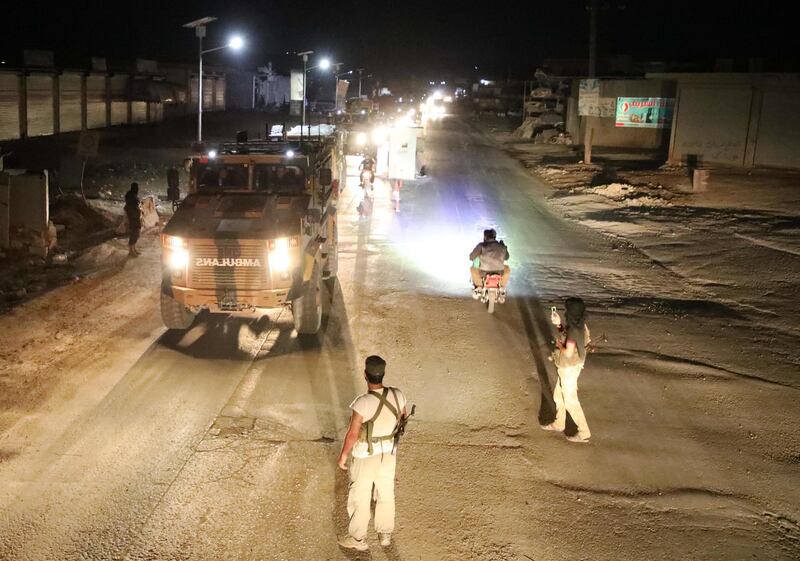 CORRECTION / Syrian anti-regime fighters gather as a convoy of Turkish military vehicles heading toward the northern Syrian Idlib province drives on a road near the town of Atareb in Syria's northwestern Aleppo province late during the night, on July 7, 2019.  Idlib and parts of neighbouring Hama, Aleppo and Latakia provinces were supposed to be protected by a buffer zone under a September 2018 agreement between Russia and Turkey. / AFP / Aaref WATAD
