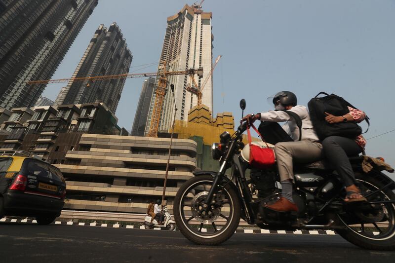 A man rides past buildings under construction in Mumbai, India, Monday, Feb 1, 2021. Indiaâ€™s government on Monday announced it will boost healthcare spend amid the coronavirus pandemic and said it was committed to the development of the financial institutions and shoring up of infrastructure to get the pandemic-ravaged nation back as the world's fastest-growing major economy.(AP Photo/Rafiq Maqbool)