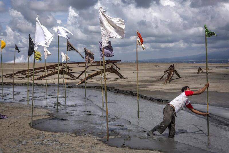 A man sets up an art installation by artist Dadang Christanto, with title 'Gombal' or 'Rags' at the mudflow during the tenth anniversary of the eruption Ulet Ifansasti / Getty Images