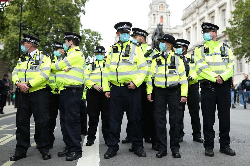 Police officers stand guard during a protest opposed to Covid-19 pandemic restrictions, in Trafalgar Square, London, UK. PA via AP