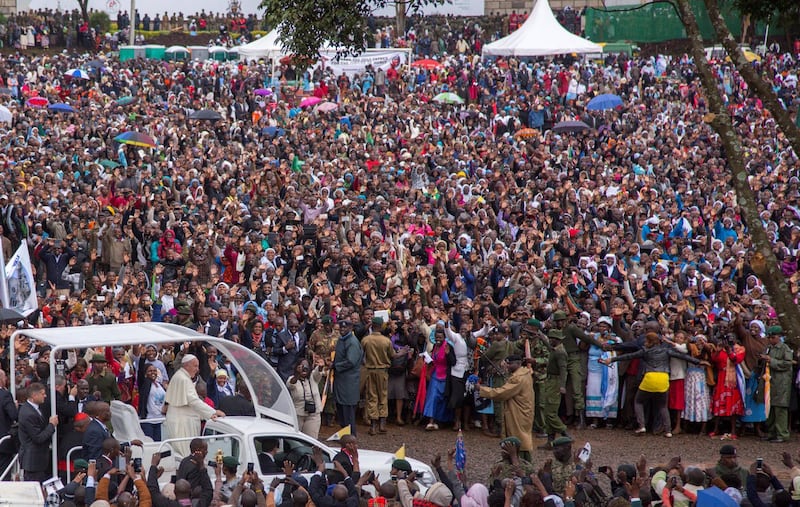 Pope Francis waves to the crowd at the University of Nairobi as he arrives to deliver an open-air mass on November 26, 2015. Pope Francis held his first open-air mass in Africa on November 26 with huge crowds calling heavy rains "God's blessing" as they sung and danced in the Kenyan capital. The 78-year-old pontiff, the third pope to visit the continent, is also scheduled to visit Uganda and the troubled Central African Republic (CAR) on a six-day trip.  AFP PHOTO / GEORGINA GOODWIN (Photo by Georgina Goodwin / AFP)