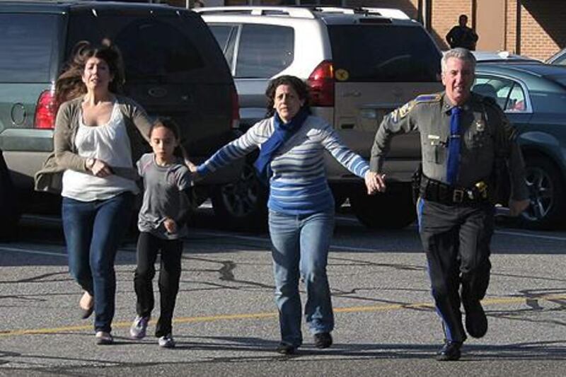 A police officer leads two women and a child from Sandy Hook Elementary School. Shannon Hicks / AP Photo/Newtown Bee.