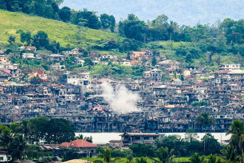 Smoke billows from destroyed buildings after government troops fired mortars at an Islamic State position in Marawi on the southern island of Mindanao on October 15, 2017. 
Philippine troops on October 15 bombed militants loyal to the Islamic State group who have held out for over four months in a southern city and the military said the conflict would be over "very soon". / AFP PHOTO / Ferdinandh CABRERA