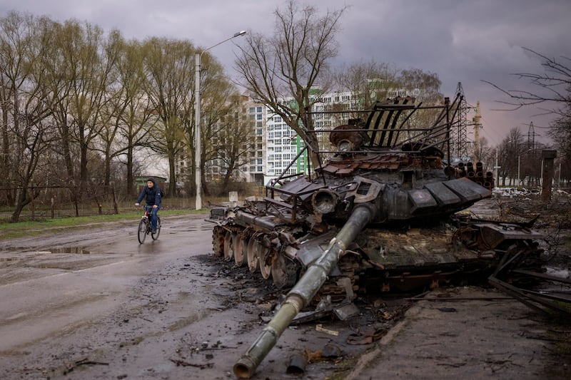 A man rides his bicycle next to a destroyed Russian tank in Chernihiv, Ukraine. AP Photo