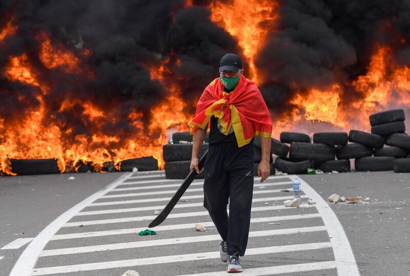 A man walks past burning tyres at the barricade. AFP