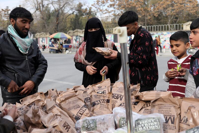 An Afghan woman buys food left behind by the US military at a stall in Kabul, Afghanistan. Reuters