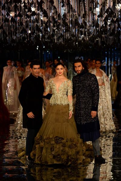 Indian bollywood actors Alia Bhat (C) and Ranveer Singh (R)  present creations by Indian fashion designer Manish Malhotra (L) during the FDCI India Couture week 2017 in New Delhi on July 30, 2017. / AFP PHOTO / SAJJAD HUSSAIN