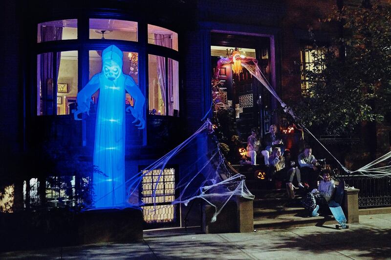 People spend time outside a house decorated for Halloween while watching revellers pass by. AP Photo