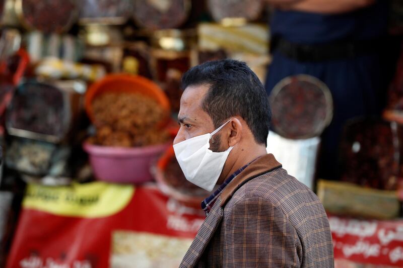 A Yemeni wearing a protective face mask passes the shops of dates, a popular appetizer for breaking the fast during Ramadan, at a market in Sanaa.  EPA