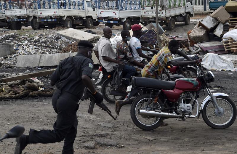 A police officer pursues fleeing motorcycle taxi riders who refused to stop at mounted barricades to check movement of vehicles and for failing to comply with the sit-at-home order to prevent the spread of COVID-19 coronavirus on Lagos Ibadan expressway.  AFP