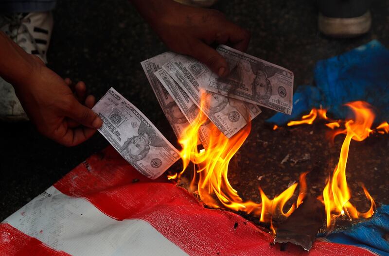 A supporter of a communist group burns representation of US currency, during a protest near the US embassy in Lebanon. AP