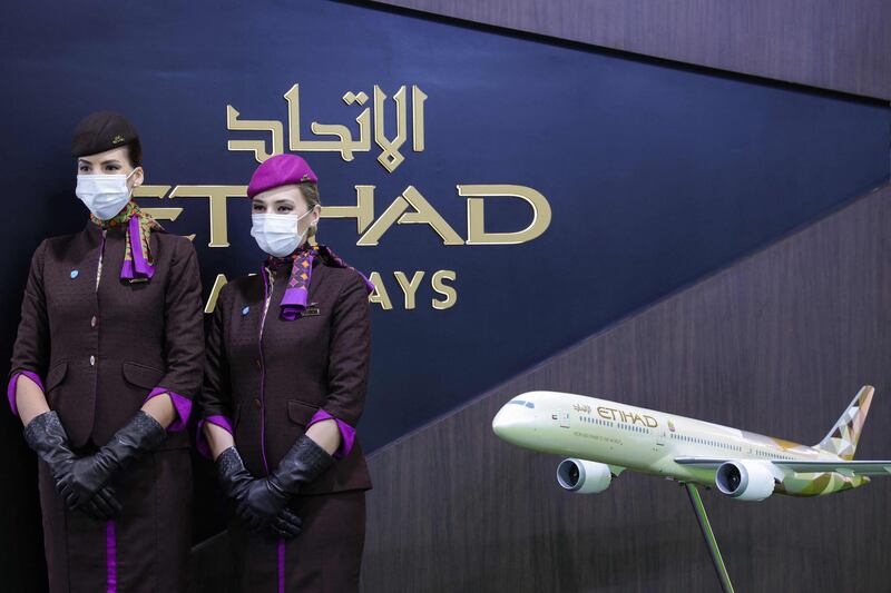 Hostesses stand by an Etihad airways airplane model at the Arabian Travel market exibition in the Gulf emirate of Dubai, on May 17, 2021. / AFP / Giuseppe CACACE
