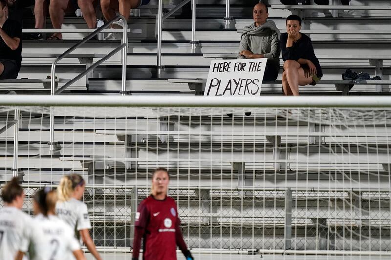 Fans watch from the stands with a sign during the first half of an NWSL soccer match between the North Carolina Courage and Racing Louisville FC in Cary, NC , Wednesday, October 6, 2021. AP Photo