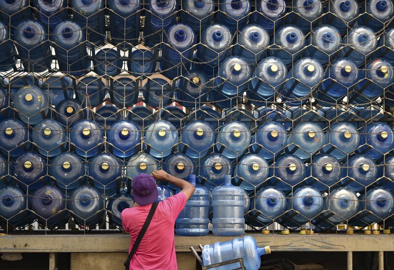 A man puts empty water containers back on a lorry belonging to a private distributor in Caracas, Venezuela. AFP