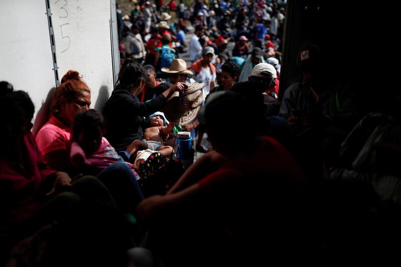 Carol Santos, a migrant from Honduras, fans her baby with a hat as they hitch a ride with fellow migrants in the back of a truck near Sayula de Aleman, Mexico. Reuters