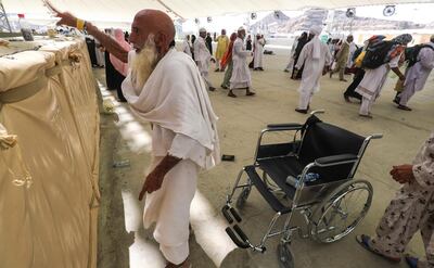 A Muslim pilgrim rises from his wheelchair to take part in the symbolic stoning of the devil at the Jamarat Bridge in Mina, near Mecca, which marks the final major rite of the hajj on August 23, 2018. - Muslims from across the world gather in Mecca in Saudi Arabia for the annual six-day pilgrimage, one of the five pillars of Islam, an act all Muslims must perform at least once if they have the means to travel to Saudi Arabia. (Photo by AHMAD AL-RUBAYE / AFP)