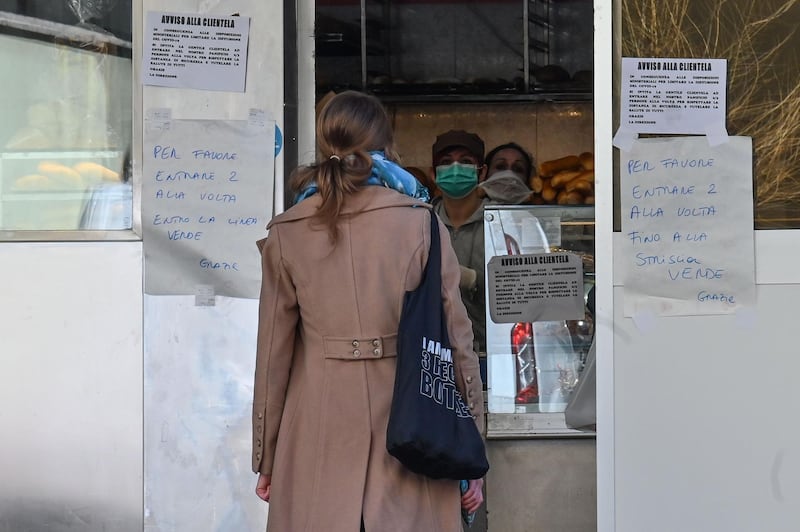 A resident waits in line to buy bread at a bakery in Rome's Monteverde Vecchio district. AFP
