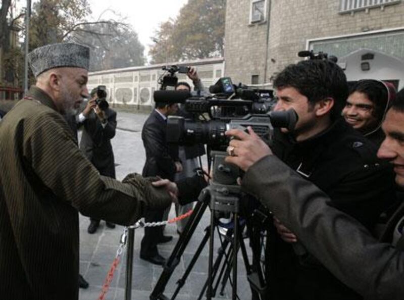 The Afghanistan president Hamid Karzai, left, greets journalists after the Eid al Adha prayers at the Presidential Palace mosque in Kabul, Afghanistan, on Friday, November 27, 2009.