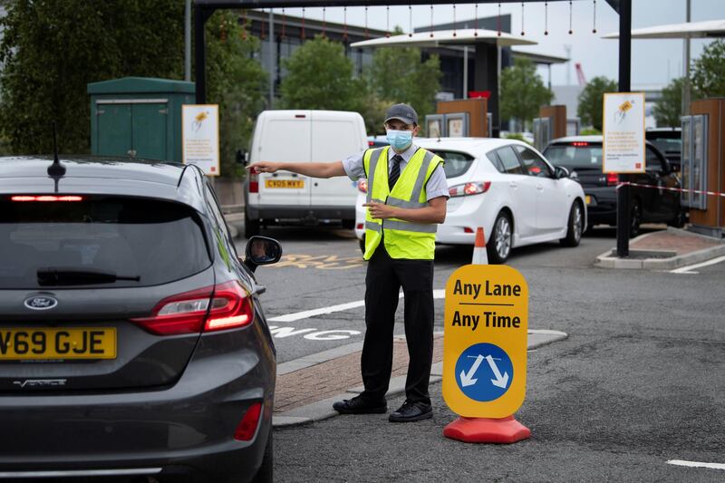 SWANSEA, UNITED KINGDOM - JUNE 03: A worker at a McDonald's restaurant wears a surgical face mask as he ushers cars into a drive-through lane on June 03, 2020 in Swansea, United Kingdom. The restaurant has reopened its doors for drive-through customers only. The Welsh government has further relaxed COVID-19 lockdown measures this week, allowing people from different households to meet up outside while maintaining social distancing. Schools have remained closed and those who have been advised to shield at home can go outside again but have been told to avoid shopping. (Photo by Matthew Horwood/Getty Images)