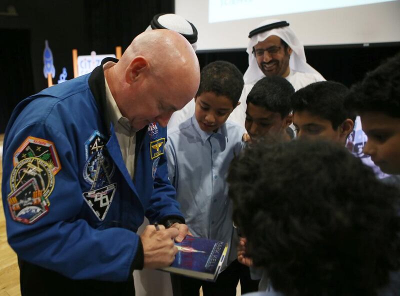 Retired US astronaut Scott Kelly autographs a book for pupils at an event in Abu Dhabi on Monday to unveil Citizen Science, a mobile platform for students. Ravindranath K / The National