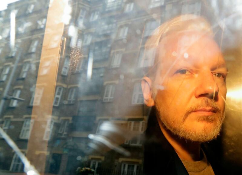 FILE- In this May 1, 2019 file photo, buildings are reflected in the window as WikiLeaks founder Julian Assange is taken from court, where he appeared on charges of jumping British bail seven years ago, in London,. Assangeâ€™s partner revealed Sunday that she had two children with him while he lived inside the Ecuadorian Embassy in London and she issued a plea for the WikiLeaks founder to be released from prison over fears for his health during the coronavirus pandemic.(AP Photo/Matt Dunham, File)