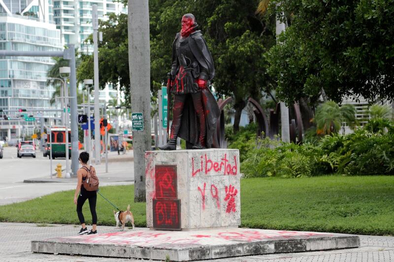 A woman walks past a vandalised statue of Juan Ponce de León at Bayfront Park in Miami. AP Photo