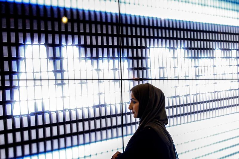 epa06330338 A woman pictured against the a display reading 'Abu Dhabi' at a booth during the Fintech Festival in Singapore, 15 November 2017. The second edition of the Fintech Festival, the largest of its kind internationally, brings together 300 exhibitors in the world of FinTech from 13 to 17 November.  EPA/WALLACE WOON