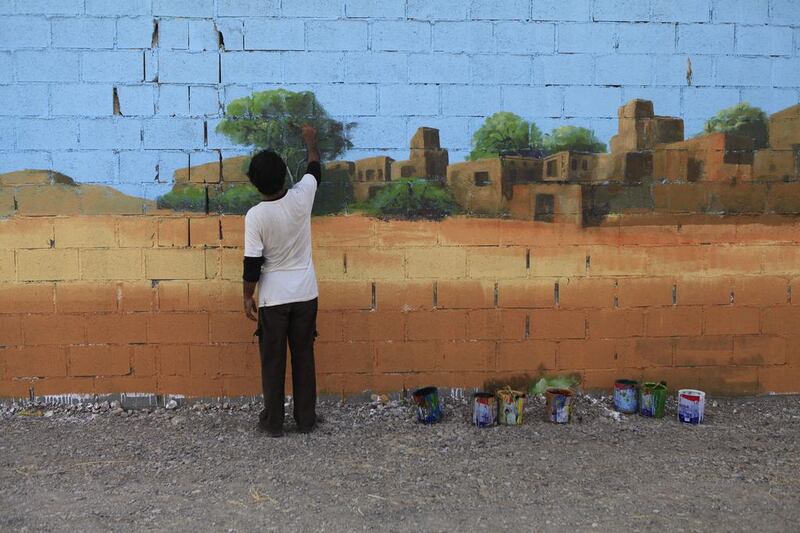 A worker completes a mural on an exterior wall at the newly opened Rak Zoo.  Sarah Dea / The National