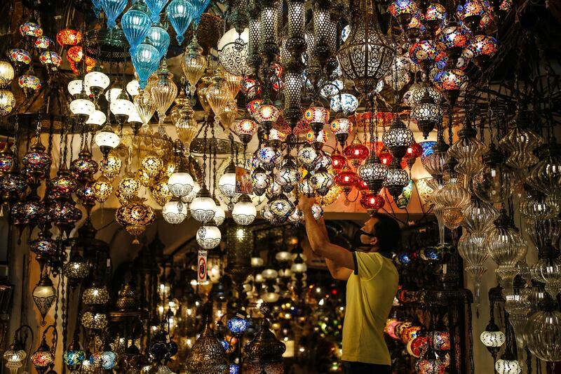 A vendor, wearing a protective face mask against the spread of coronavirus, adjusts Turkish traditional-style lanterns, at the iconic 15th century Grand Bazaar in Istanbul as it reopens following weeks of closure due to the coronavirus pandemic. AP Photo