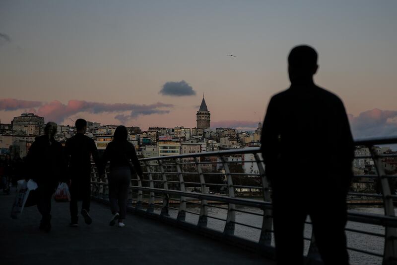 Backdropped by the iconic Galata Tower, people walk on a bridge over the Golden Horn in Istanbul, Turkey. AP