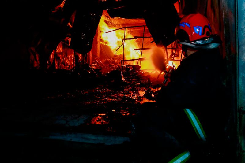 A firefighter attempts to put out the flames after the multi-storey commercial building caught fire before collapsing. AP