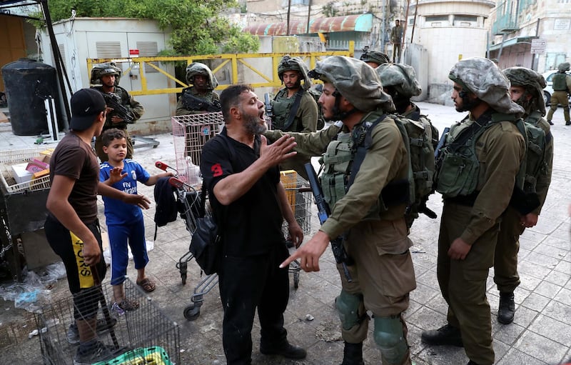 Israeli soldiers on patrol stop Palestinians in the Old City of the West Bank town of Hebron, May 17.  EPA