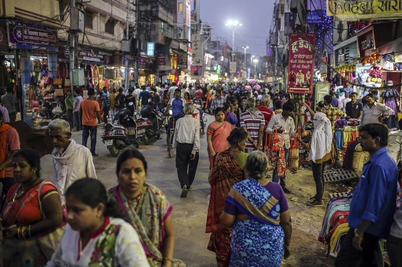 Pedestrians and shoppers walk past stores on a street in Varanasi, Uttar Pradesh, India, on Saturday, Oct. 29, 2017. A big drop in borrowing costs for Indian state lenders on perpetual bond offerings shows that the government’s surprise $32 billion capital pledge last week has finally managed to turn around market sentiment. Photographer: Dhiraj Singh/Bloomberg
