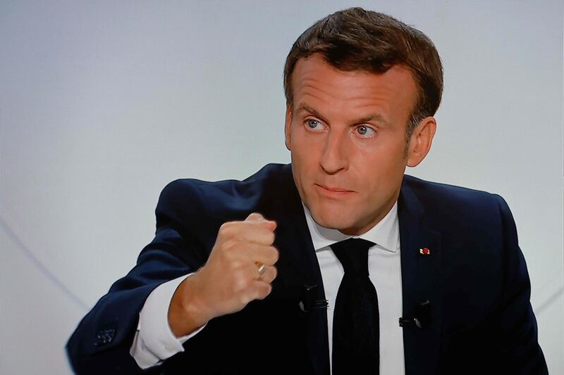 This picture shows a screen displaying French President Emmanuel Macron as he addresses the nation during a televised interview from the Elysee Palace concerning the situation of the novel coronavirus Covid-19 in France, in Paris on October 14, 2020. President Emmanuel Macron on October 14, 2020 ordered a nighttime curfew for Paris and eight other French cities to contain the rising spread of Covid-19 in the country. In a televised interview, Macron said residents of those cities would not be allowed to be outdoors between 9:00 pm (1900 GMT) and 6:00 am (0400 GMT) from Saturday, for a duration of at least four weeks. "We have to act. We need to put a brake on the spread of the virus," Macron said, adding the measure would stop people visiting restaurants and private homes in the late evening and night. / AFP / Ludovic MARIN
