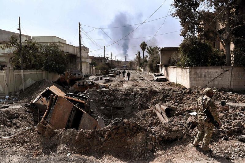 An Iraqi forces member stands next to a crater made by an air strike in west Mosul as Iraqi troops continue battling ISIL fighters to further advance inside the city on March 7, 2017.  Aris Messinis/AFP

