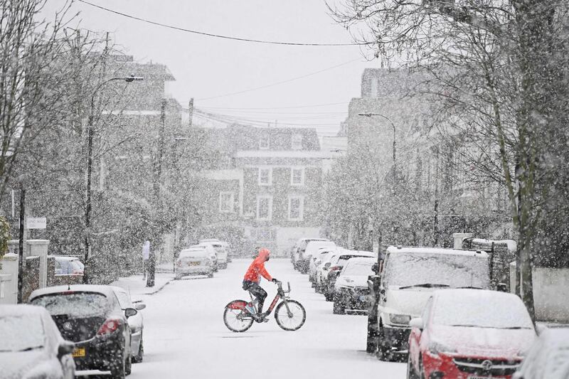 A cyclist crosses a snow-covered road in west London, as the capital experiences a rare covering of snow on Sunday. AFP