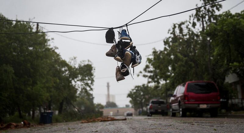 Shoes tied to a power line hang near a street after winds from Hurricane Harvey brought down a power pole in Corpus Christi, Texas. Nick Wagner / Austin American-Statesman via AP