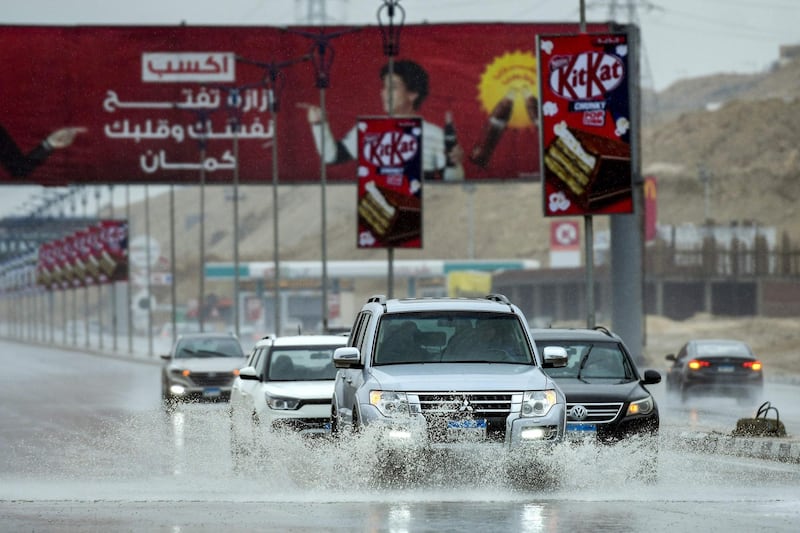 Cars drive along a flooded motorway in Cairo. AFP