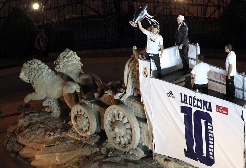 Real Madrid's captains Iker Casillas, left, and Sergio Ramos, second left, show their Champions League trophy to supporters as they stand over the Cibeles statue at Cibeles Square in Madrid during a victory rally following the Champions League final. Alberto Martin / EPA / May 24, 2014