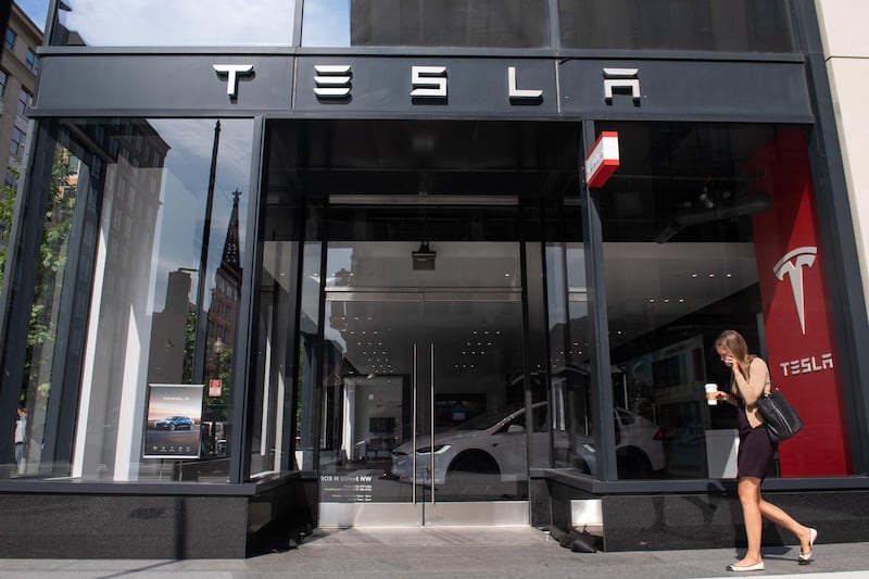 A woman walks past a Tesla showroom in Washington, DC, on August 8, 2018. - Tesla's board of directors said Wednesday it will evaluate chief executive Elon Musk's proposal to take the electric car maker private. After Musk last week raised the idea as a better solution for Tesla's long-term growth, directors met "several times" and are "taking the appropriate next steps to evaluate this," the board said in a brief statement issued before the stock market opened. (Photo by SAUL LOEB / AFP)