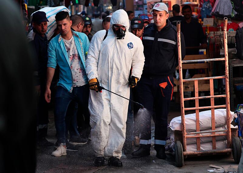 A civil defense worker wearing a protective suit sprays disinfectant as a precaution against the new coronavirus, in the main market, Baghdad. AP Photo