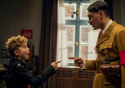 This image released by Fox Searchlight Pictures shows, from left, Roman Griffin Davis and Taika Waititi in a scene from the WWII satirical film "Jojo Rabbit." The film is nominated for a Golden Globe for best motion picture comedy.  (Kimberley French/Fox Searchlight Pictures via AP)