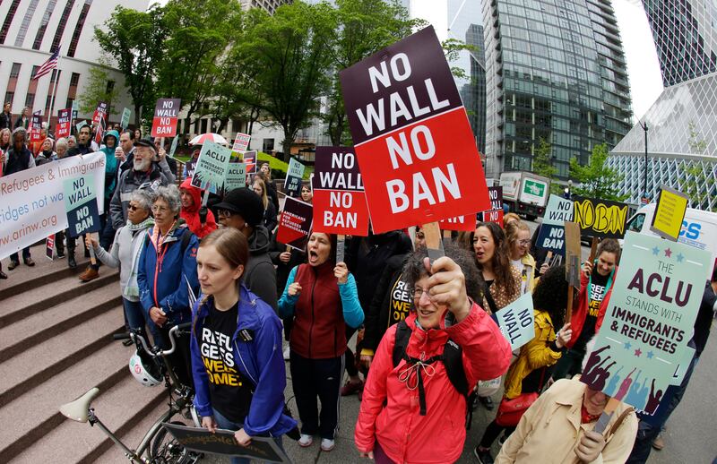 FILE - In this May 15, 2017 file photo, protesters wave signs and chant during a demonstration against President Donald Trump's revised travel ban outside a federal courthouse in Seattle. 9th U.S. Circuit Court of Appeals in San Francisco on Thursday, Sept. 7, 2017, rejected the Trump administration's limited view of who is allowed into the United States under the president's travel ban, saying grandparents, cousins and similarly close relations of people in the U.S. should not be prevented from coming to the country. (AP Photo/Ted S. Warren, File)