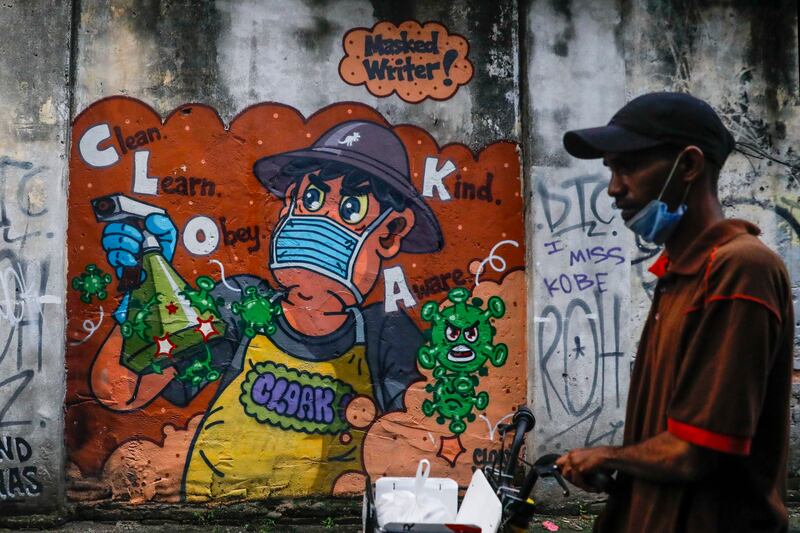 A man walks past pandemic-inspired graffiti in Kuala Lumpur. Photo: EPA