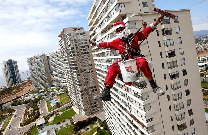 A worker waves as he cleans the windows of a building, dressed as Santa Claus, in Concon, Chile. Reuters