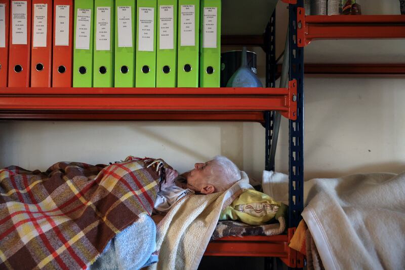 A Greek woman sleeps on a shelf after her home in Palamas was flooded during Storm Daniel on Saturday.
