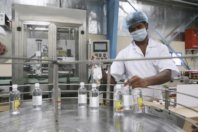A worker collects completed bottles of white vinegar from an assembly line at the Chilly Willy manufacturing facility in Dubai, June 3, 2015.